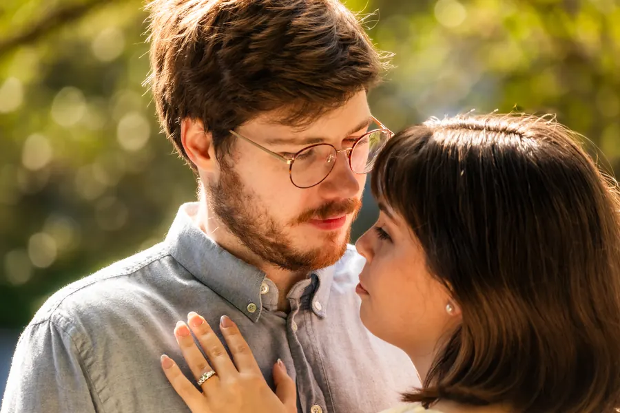 Her hand with the engagement ring resting on his chest, faces close