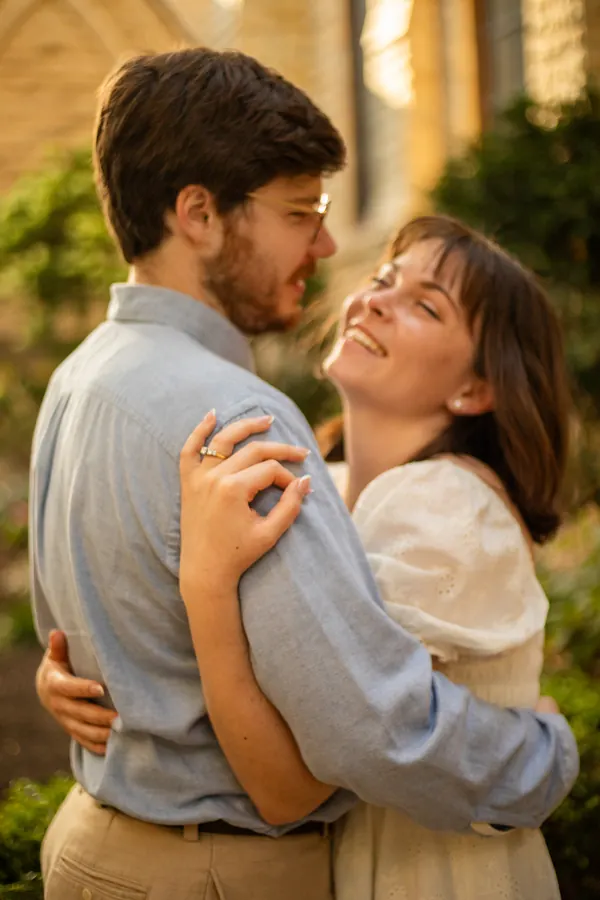 She laughs with her head back, held close, in golden light