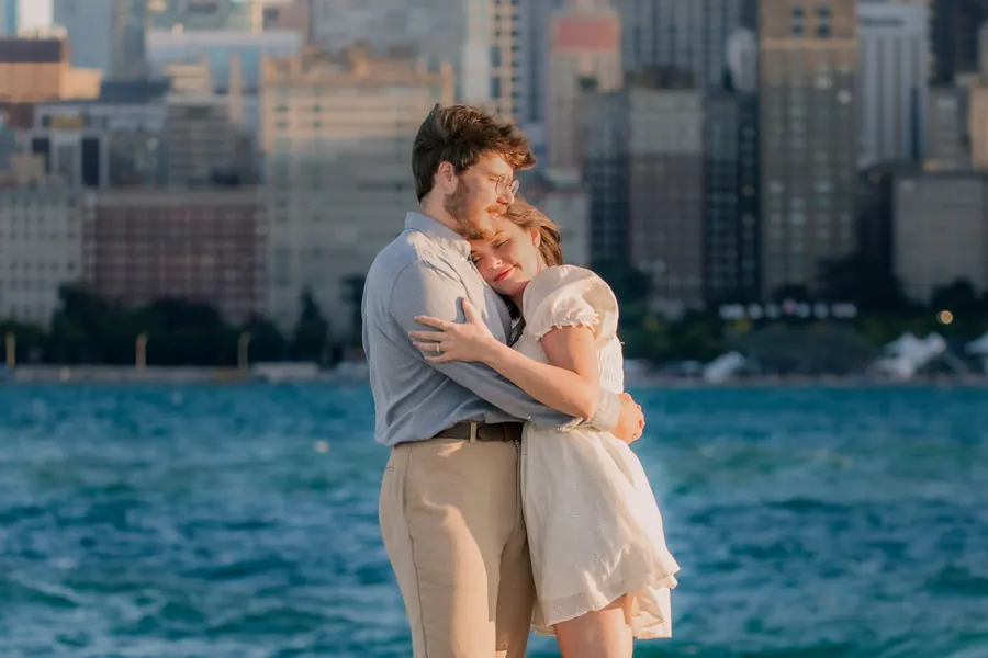 The two of them holding each other by the water, her eyes closed